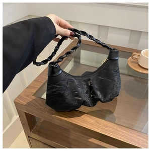 Detail of black pleated cloud bag featuring woven handle and smooth metallic zipper