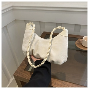 Detail of cream white pleated cloud bag featuring woven twisted handle and soft texture