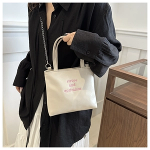 Détail du sac cabas blanc avec broderie rose et bandoulière en chaîne métallique argentée