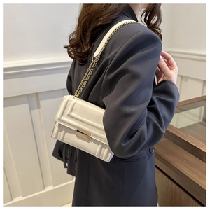 Detail of white square crossbody bag showing geometric texture and gold metal clasp