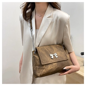Close-up of vintage brown leather bag with silver butterfly buckle and chain strap