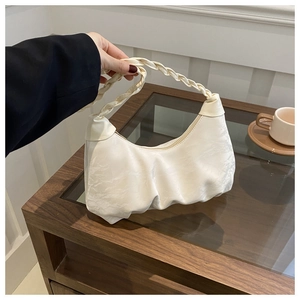 Detail of white pleated cloud bag featuring a thick braided handle and soft faux leather texture