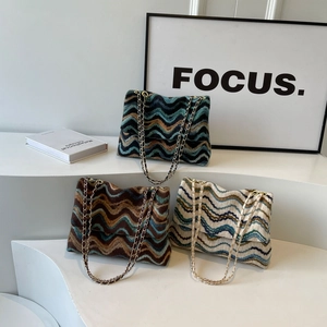 Three retro knitted crossbody bags with wave patterns and gold chain straps displayed on steps