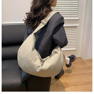 Detailed view of beige crescent hobo bag with adjustable strap worn by a model