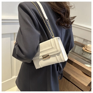 Chic white leather shoulder bag with gold chain strap shown on model in a modern setting