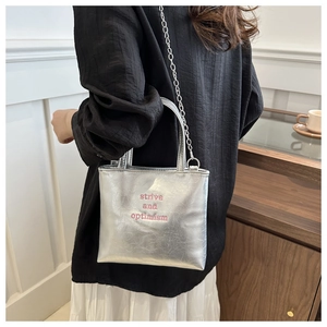 Détail d'un sac à main argenté métallisé avec broderie strive and optimism rose