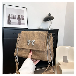 Detail of vintage brown leather tote bag with silver butterfly chain and metal buckle decoration