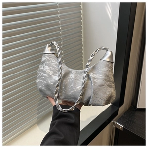 Detail of silver pleated crescent bag with woven handle and metallic finish texture