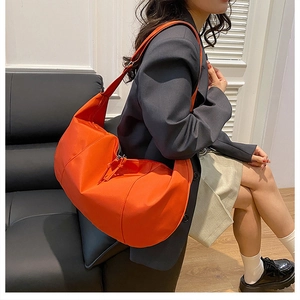 Detail of bright orange waterproof nylon dumpling bag with wide shoulder strap