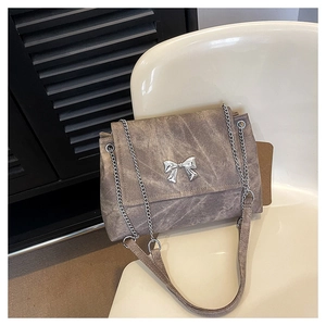Detail of grey stone textured crossbody bag featuring a silver metal butterfly clasp