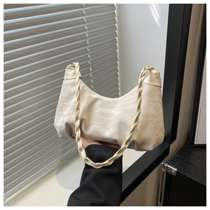 Detail of cream pleated cloud bag featuring a unique twisted rope shoulder strap design