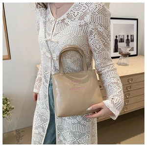 Détail d'un sac à main kaki brodé avec bandoulière chaîne porté par un mannequin