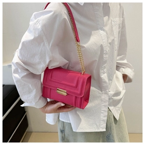 Detail of neon pink rectangular crossbody bag with geometric texture and gold chain strap