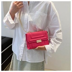 Detail of hot pink crossbody bag with gold chain strap on white oversized shirt outfit