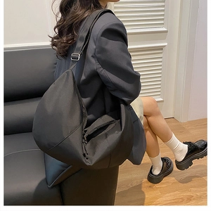 Detail of black nylon half-moon crossbody bag with wide adjustable shoulder strap and metal buckle