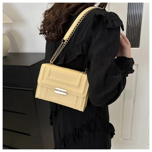 Detail of light yellow square crossbody bag featuring linear embossing and gold chain strap
