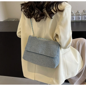Detailed back view of a light blue sequin chain bag worn with a white blazer