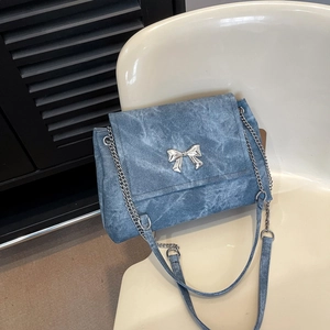 Blue denim tote bag with silver butterfly chain and strap on a white chair