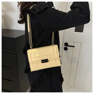 Detail of a beige square crossbody bag with geometric texture and elegant gold chain strap