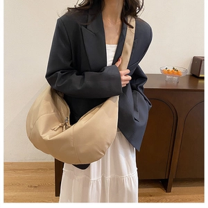 Detail view of the large beige moon bag with adjustable shoulder strap on a model