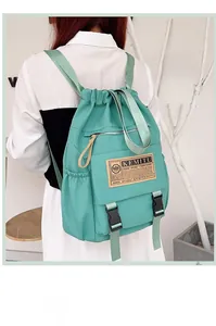 Detail of mint green school backpack with drawstring closure and black plastic buckles
