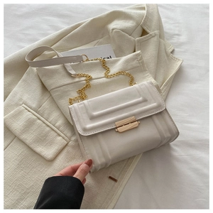 Detail of off-white leather square bag featuring textured pattern and golden metal buckle