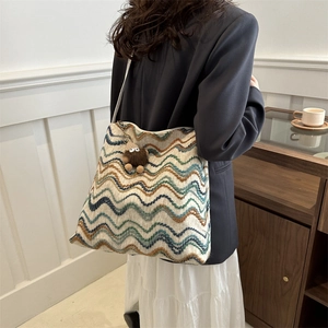 Detail of colorful striped woven tote bag with a small brown monster pendant on the side