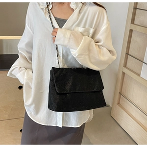 Close-up of black sequin tote bag with classic chain strap on model for styling