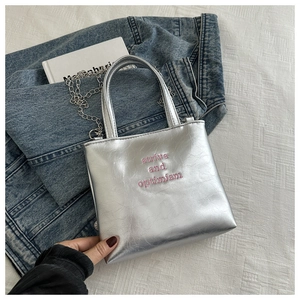 Détail du sac seau argenté avec broderie rose et chaîne en métal élégante