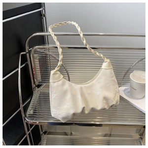 Close-up of cream pleated crescent bag featuring a woven handle and satin fabric texture