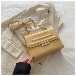 Detail of light yellow crossbody bag with geometric stripes and golden metal buckle