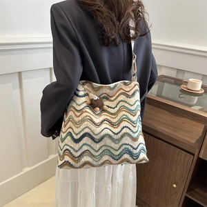 Close-up of wave pattern woven tote bag with a brown plush monster charm on it