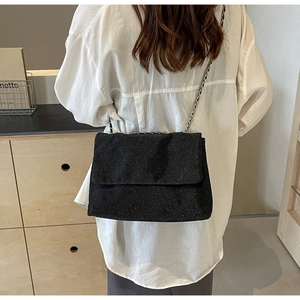 Detail of a sparkling black sequin chain tote bag worn over a white shirt