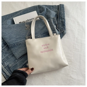 Détail du sac cabas en PU crème avec broderie rose et bandoulière en chaîne