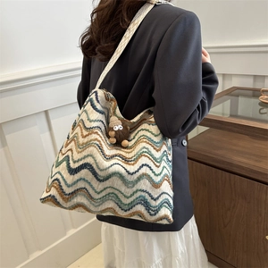 Detail view of the colorful zigzag knit tote bag with a geometric strap and plush charm