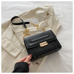 Detail of minimalist black PU crossbody bag with golden metal buckle and chain strap