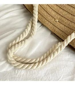 Detailed macro view of woven straw tote bag with braided cotton rope handle and studs