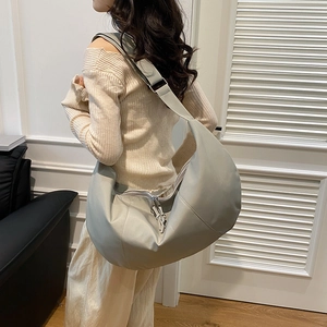 Large light grey-green minimalist crescent tote bag with soft leather texture and strap