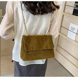 Detailed view of the gold sequined tote bag with a metallic chain strap on a model