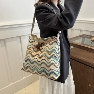 Detail of colorful wavy striped velvet tote bag with a small plush monkey charm accessory