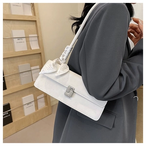 Détail du sac sous l'aisselle en cuir blanc avec boucle en cristal et foulard en soie