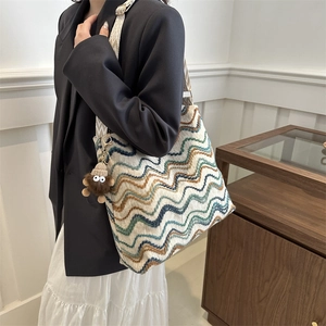 Chic knit tote bag with multicolor wave patterns shown on model in a stylish setting
