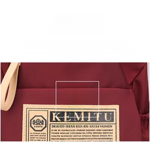 Close-up of water-resistant burgundy nylon fabric with KEMITU brand leather patch logo