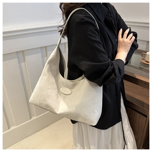 Detail of cream suede hobo bag showing the curved zip closure and delicate logo plate