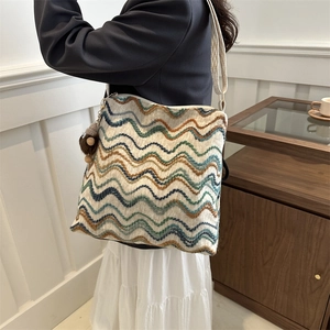 Close-up of woven velvet tote with colorful wave embroidery and plush pendant detail
