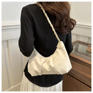 Detail of a creamy white pleated crescent bag with a unique thick braided shoulder strap