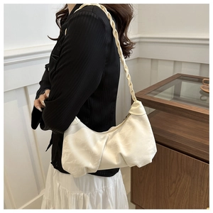 Detail of off-white pleated crescent cloud bag with woven strap shown on shoulder
