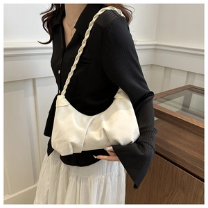 Detailed side view of white ruched shoulder bag with chunky woven strap on model