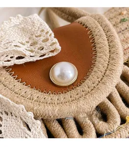 Detailed close-up of woven cotton tote bag with leather flap and pearl ornament