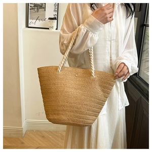 Detail of hand-woven straw tote bag featuring natural texture and white rope handles